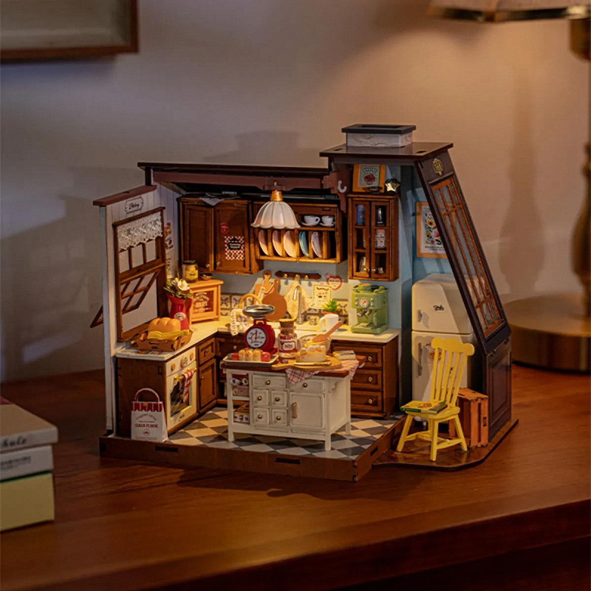 Detailed model of a miniature kitchen with various appliances and furniture on a wooden surface.