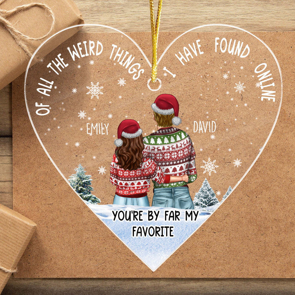 Heart-shaped clear acrylic ornament resting on brown craft paper next to wrapped holiday gifts, ideal for a couple's