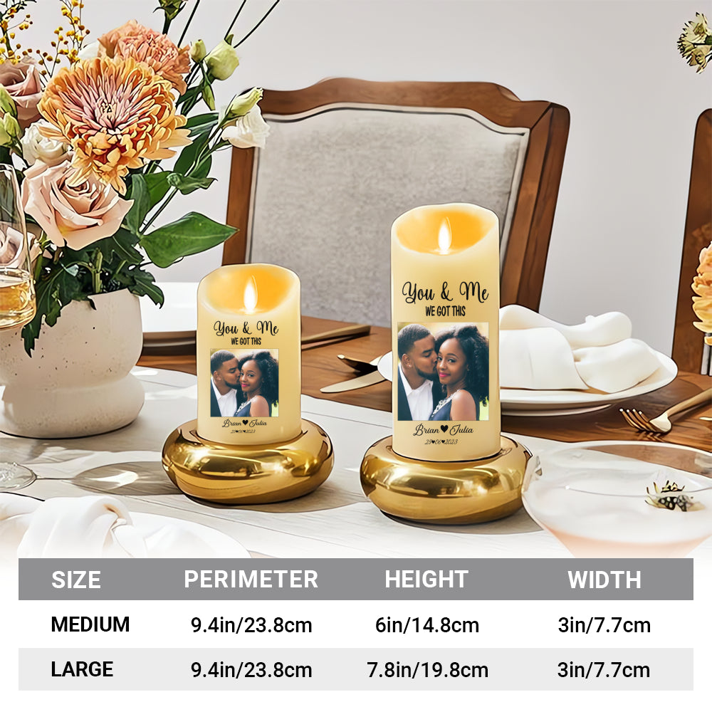 Two sizes of personalized flameless LED candles displayed on gold stands next to a vase of flowers on a dining table.