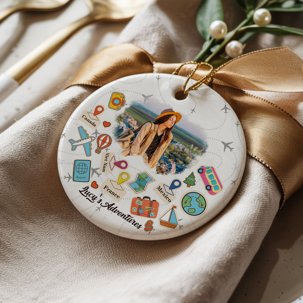 Personalized travel Christmas ornament resting on a folded napkin with a gold bow, showing custom adventure details.