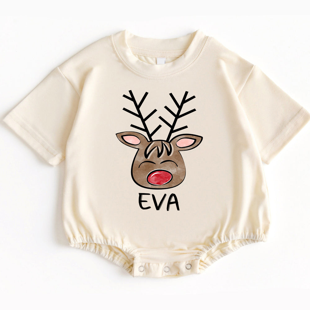 Cream short-sleeve baby romper displaying a festive reindeer face graphic with a red nose and the name EVA below it.