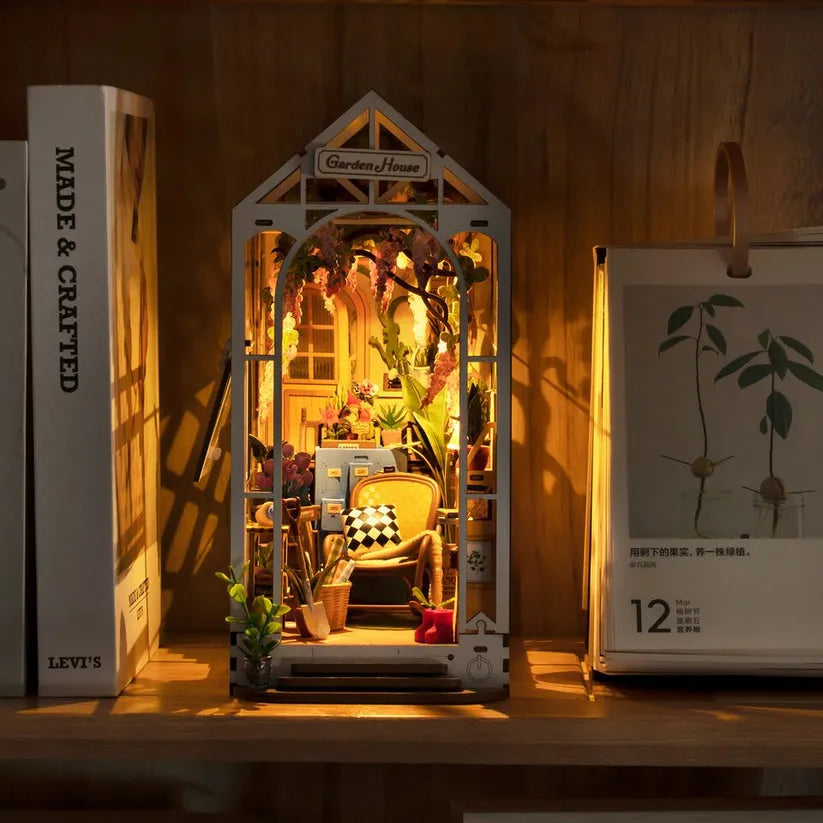 DIY wooden book nook placed between books on a wooden shelf with warm LED lighting