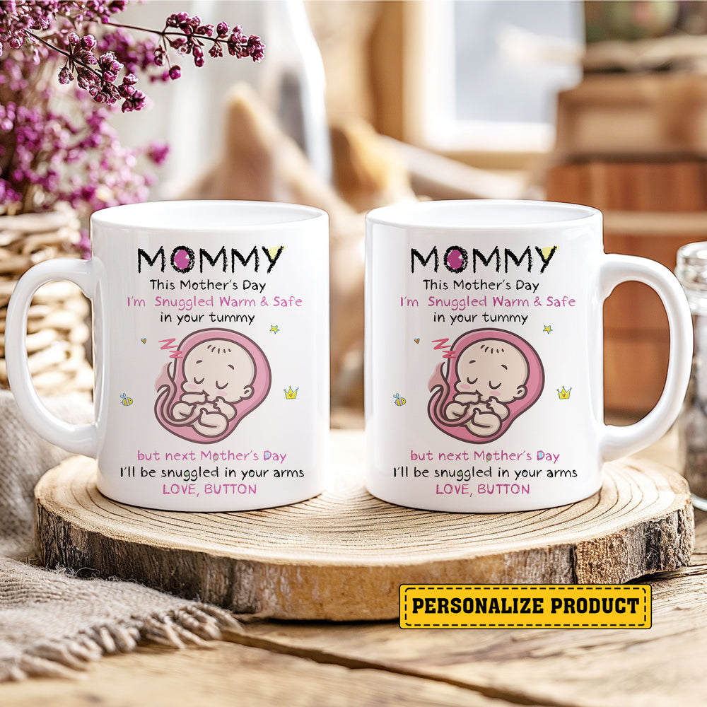 Two white ceramic mugs showcasing a custom pregnancy design on a rustic wooden slice surrounded by purple flowers.