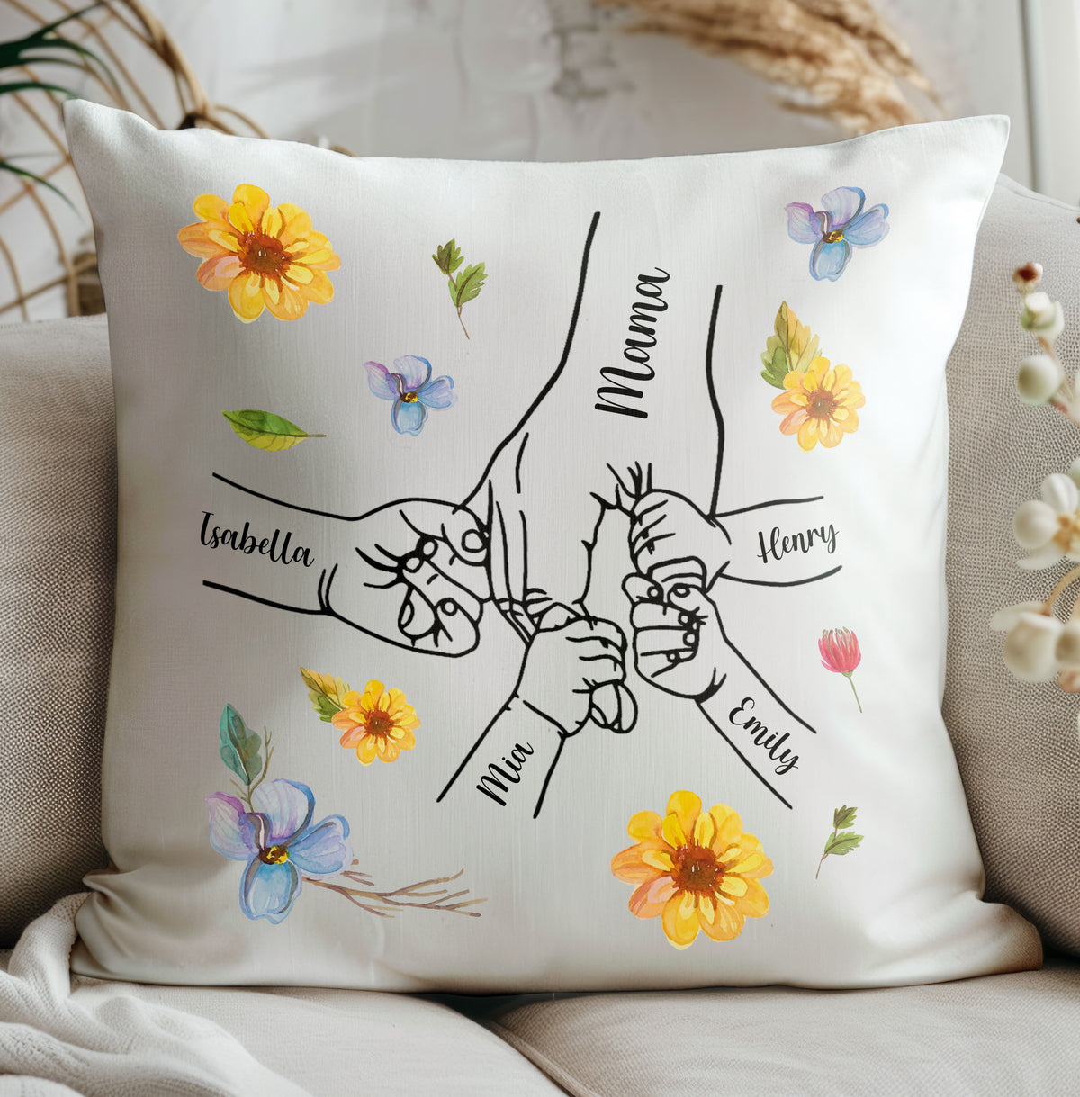 Personalized Hand in Hand Floral Pillow resting on a neutral couch, featuring custom names and watercolor flowers.