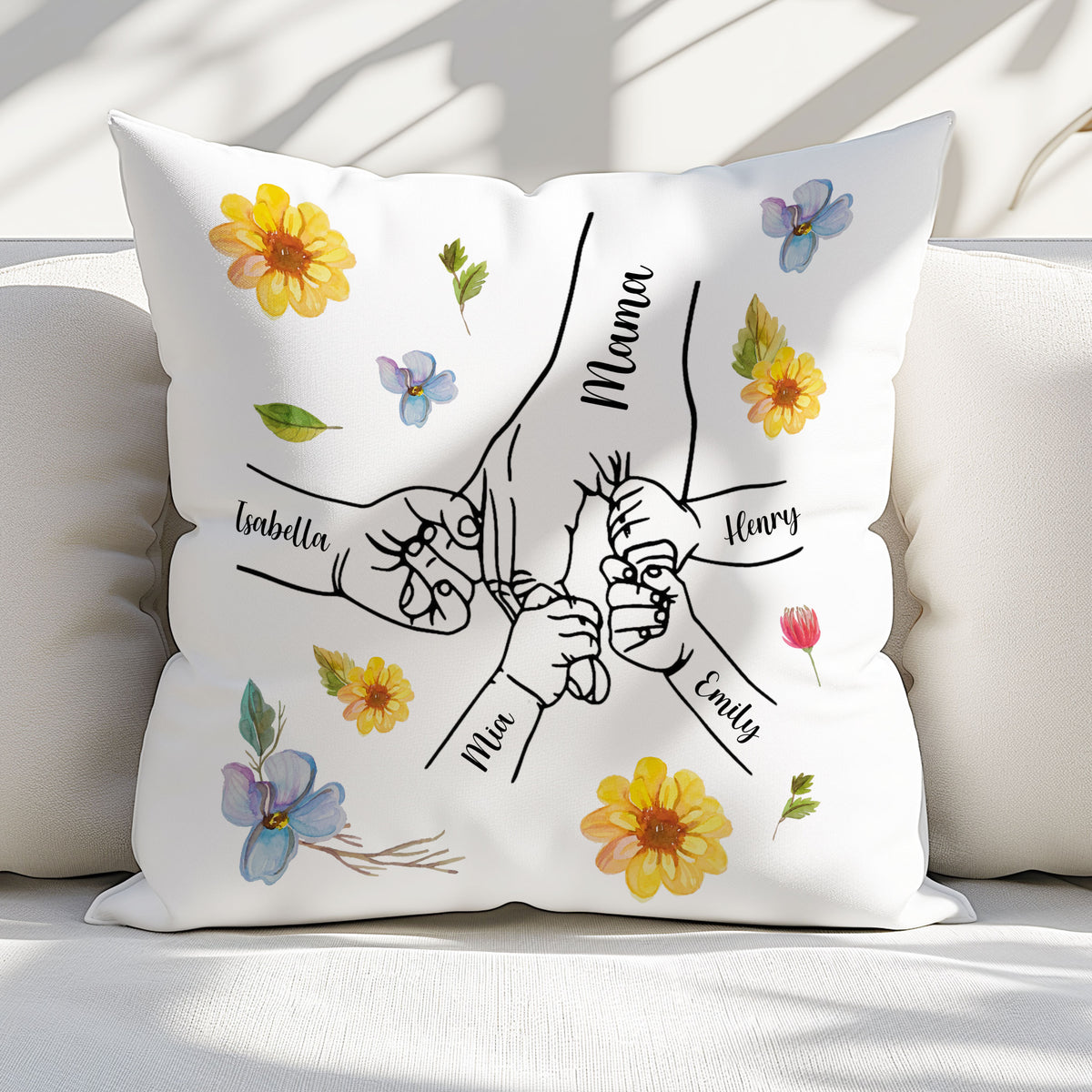 Close-up of a custom flannel throw pillow with black line-art hands and floral prints, placed on a sofa.