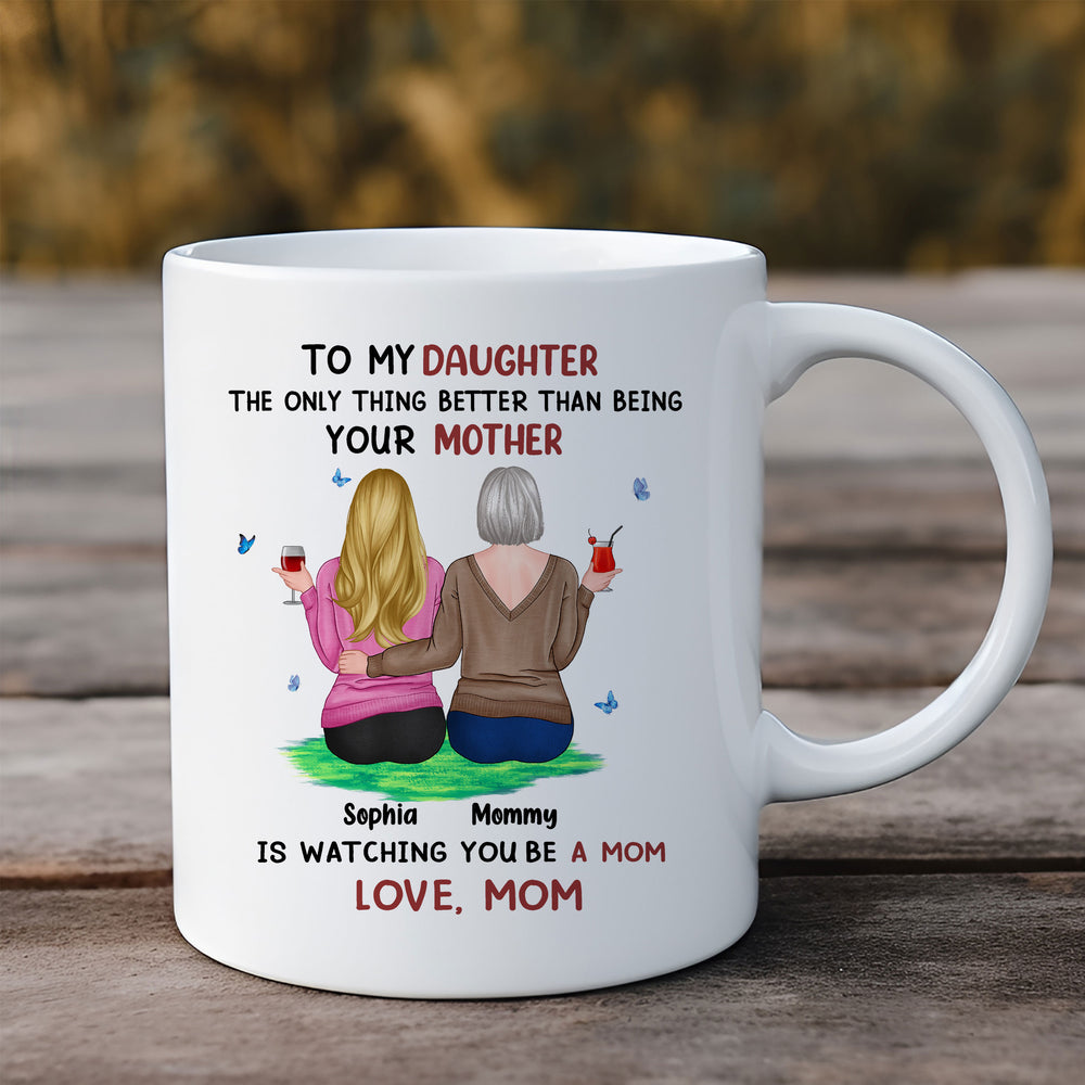 A white ceramic mug featuring a custom mother and daughter illustration sitting on a rustic wooden table outdoors.