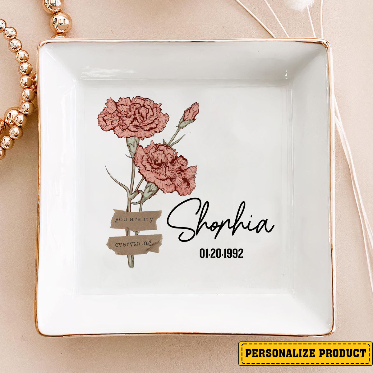 Personalized birth month flower ring dish with carnations, name, and date on a neutral background.