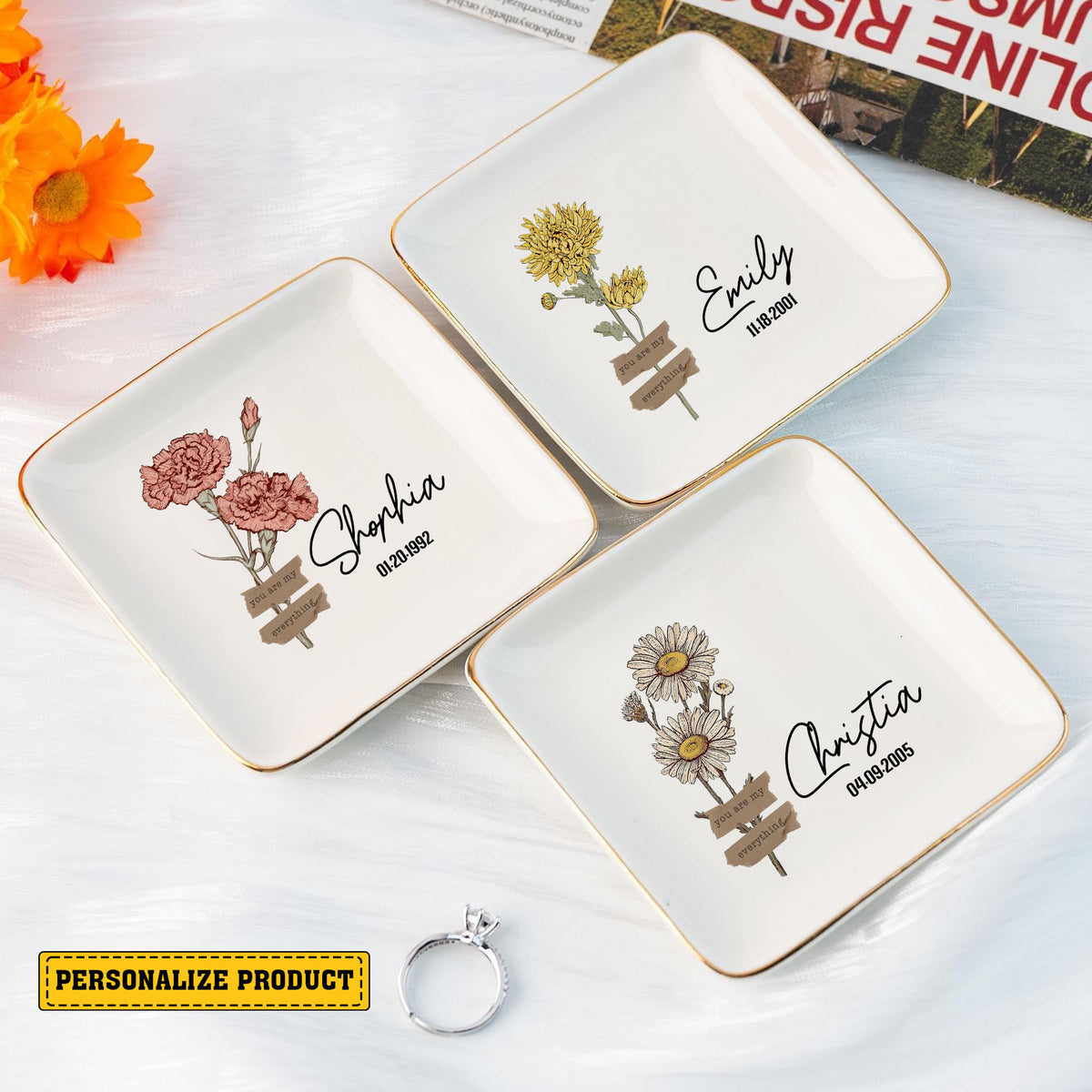Three square white ceramic ring dishes with gold rims, featuring different floral illustrations, custom names, and dates.