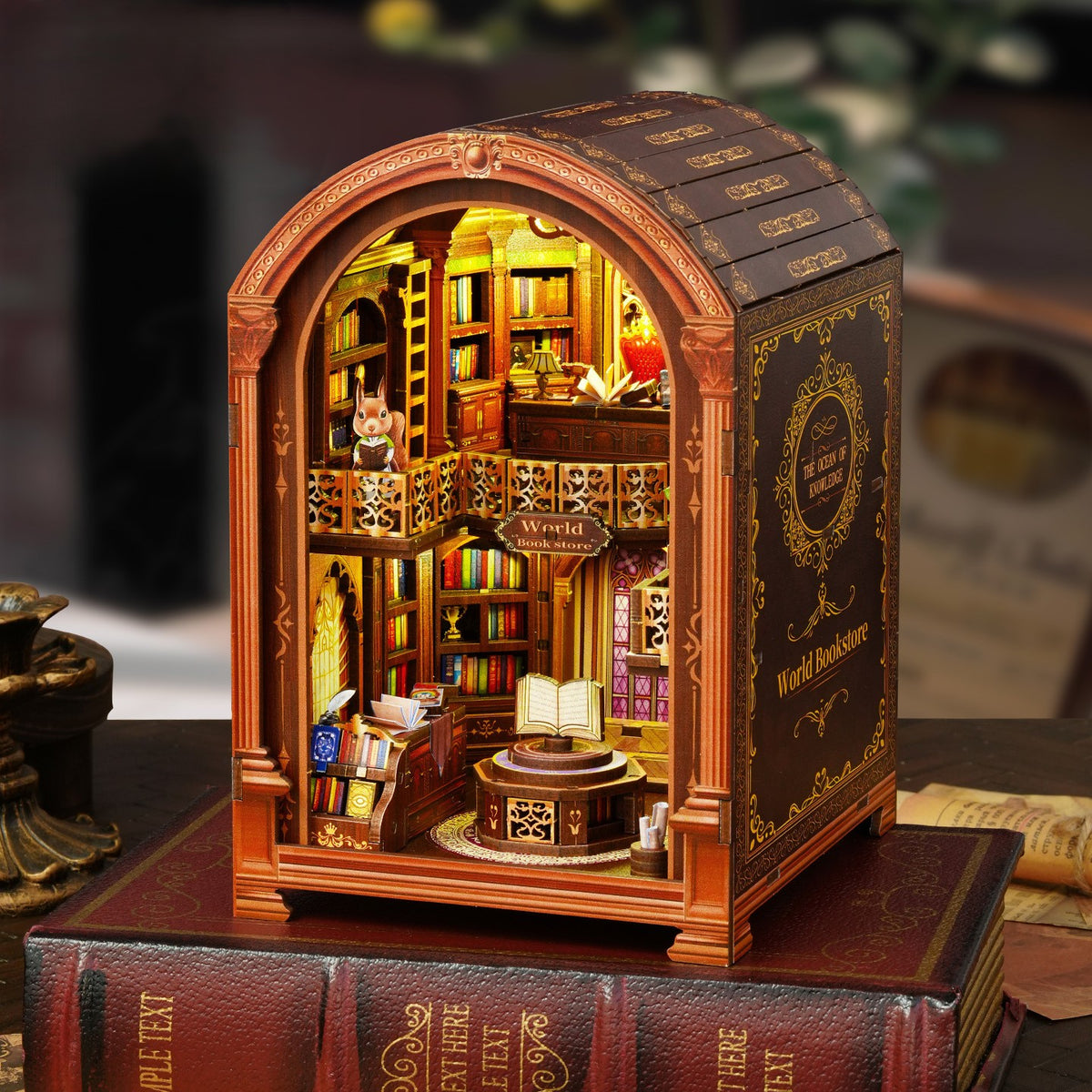 DIY miniature bookstore book nook kit lit up with warm LED lights, showing a cozy vintage library with shelves, a squirrel