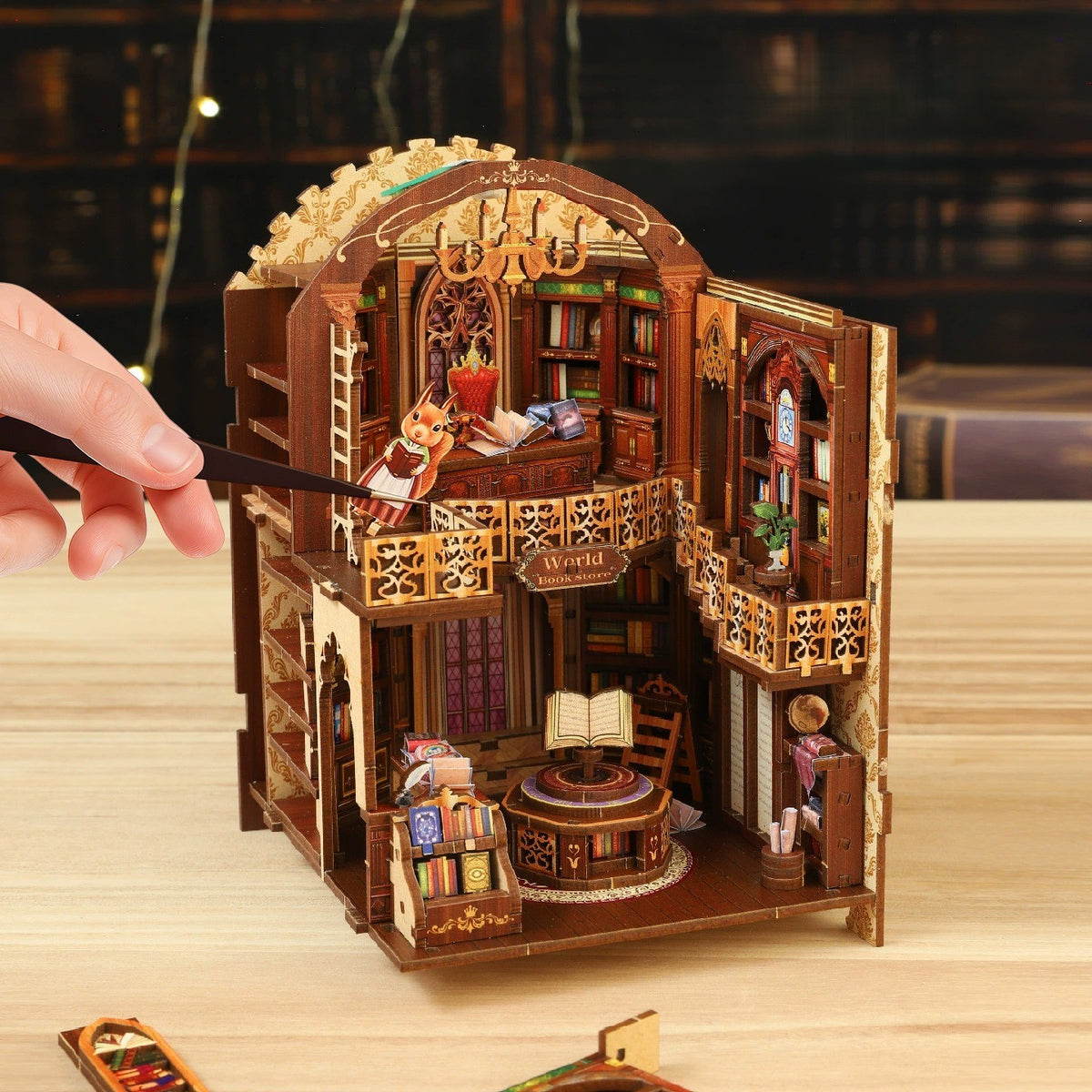 Unlit wooden bookshelf insert kit being put together with tweezers on a table, showing the multi-level interior layout and