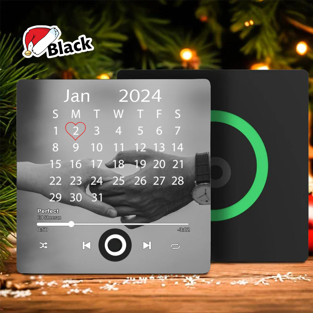 Black square fridge magnet with a calendar showing a heart on Jan 2nd, a couple's hand photo, and music player controls.