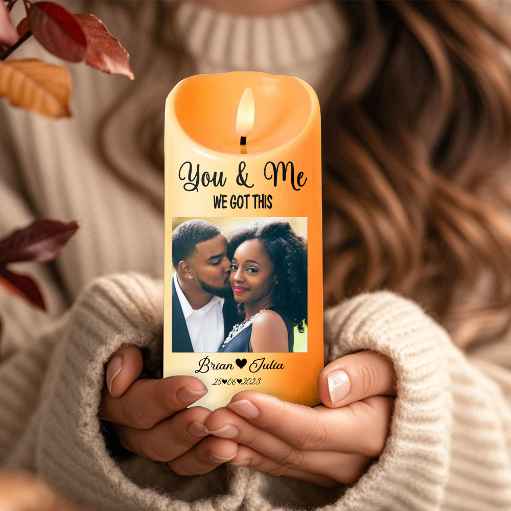 Close-up of hands holding a warm amber LED candle printed with a couple's photo, names, and a special date.
