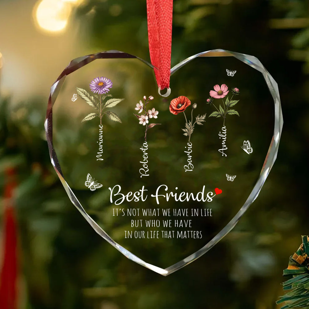 Heart glass ornament for best friends hanging on a green Christmas tree branch with a red ribbon and festive holiday