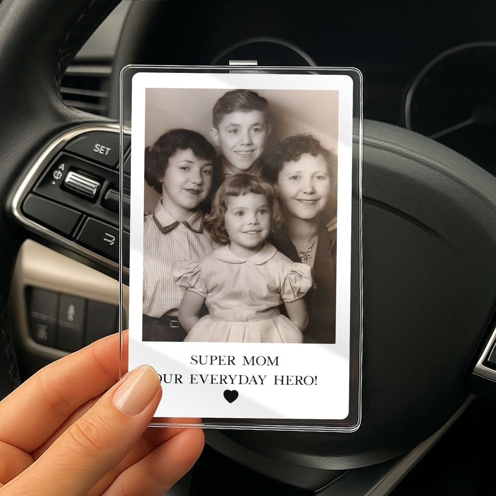 A hand holds a custom clear acrylic car visor photo clip featuring a vintage family photo and text reading 'Super Mom Our