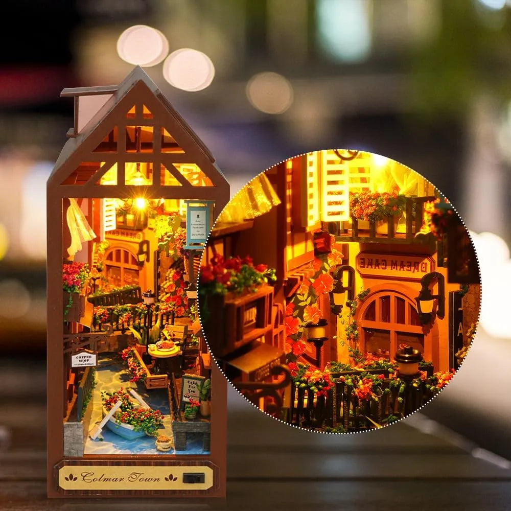 Close-up of the illuminated French cottage miniature puzzle featuring warm LED lights, flowering balconies, and alleyway