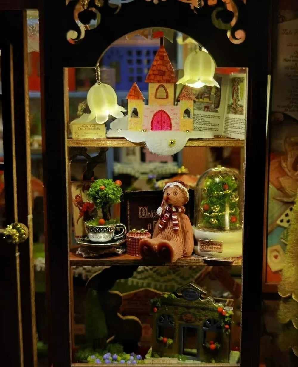 Close-up of book nook puzzle interior showcasing a tiny pink castle, teddy bear, and lit displays