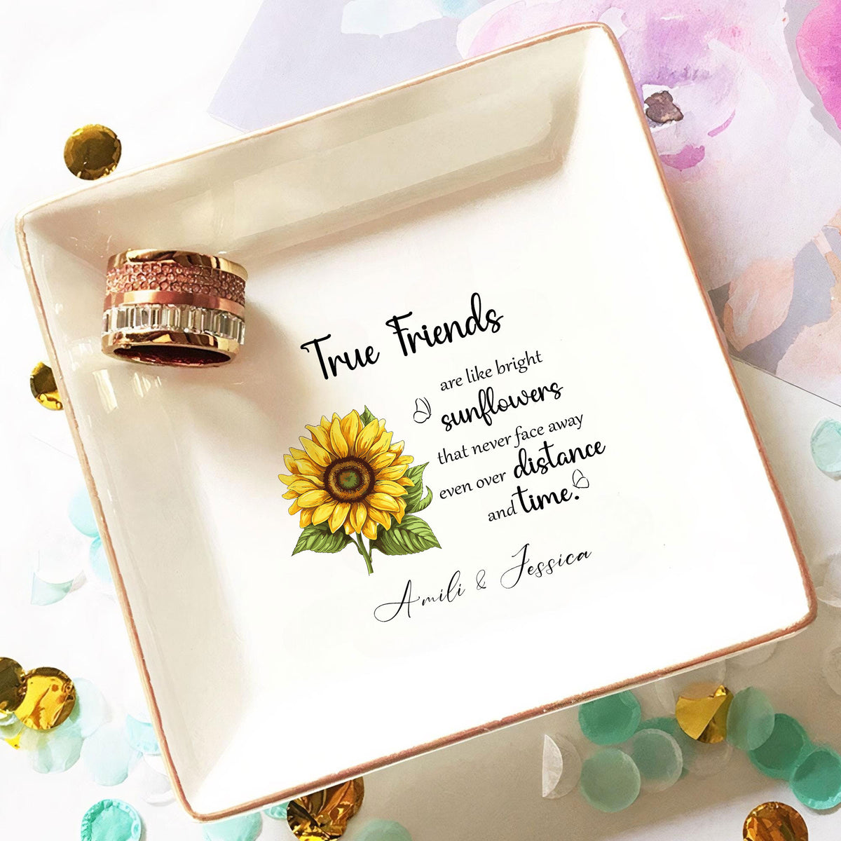 Personalized trinket tray holding a sparkling ring with confetti and decorative background elements.