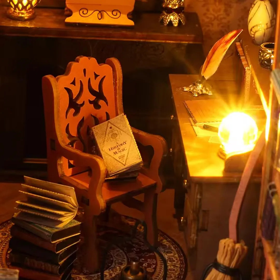 Close up view of the library book nook kit interior featuring a cozy armchair, stack of books, desk, and warm glowing orb