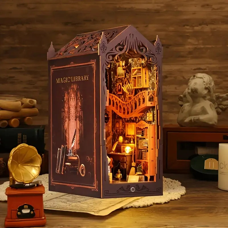Magic Library Book Nook Kit assembled on a wooden table with miniature decor and a warm lit interior glowing through its