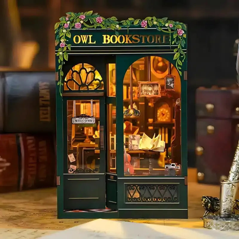 Lit DIY Owl Bookstore book nook kit showing warm interior lighting, bookshelves, and miniature display.