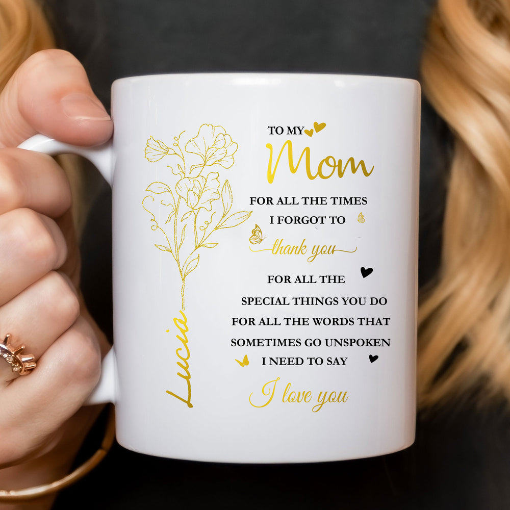 Close-up of a personalized mom ceramic mug held by a person wearing a dark top, showing gold lettering.